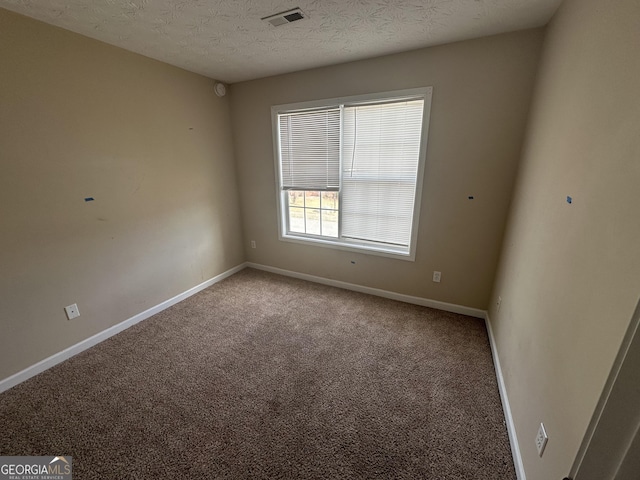 carpeted empty room with a textured ceiling