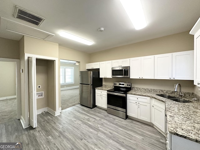 kitchen featuring sink, stainless steel appliances, light stone counters, light hardwood / wood-style floors, and white cabinets