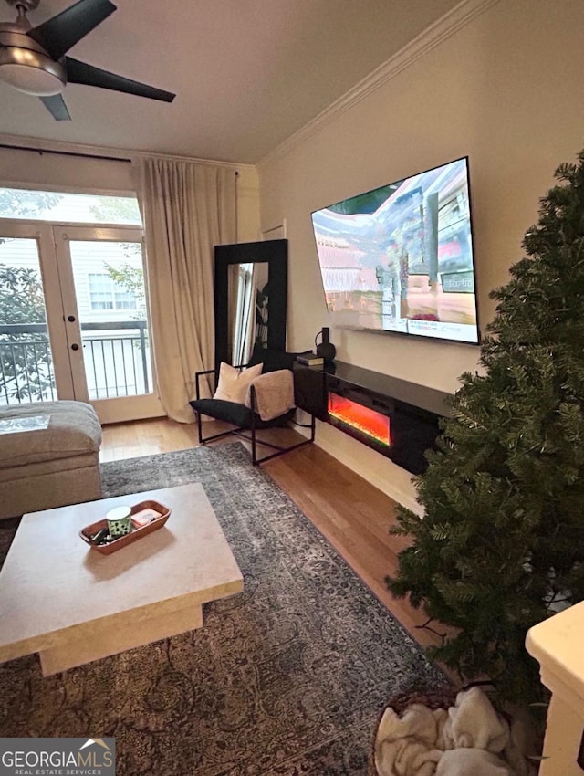 living room with hardwood / wood-style flooring, ceiling fan, and ornamental molding