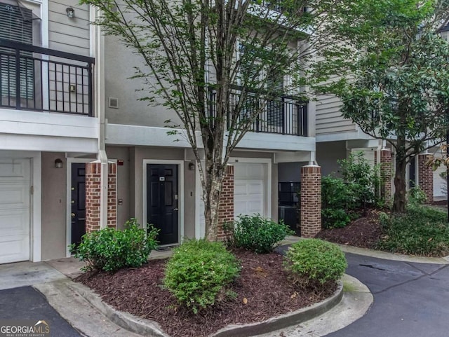 4248 River Green Dr NW Unit 312, Atlanta, GA 30327 - view of exterior entry featuring stucco siding, a garage, a balcony, and brick siding