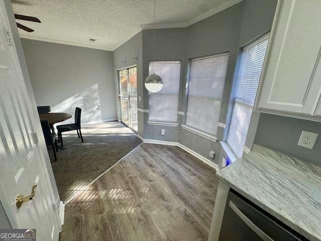 unfurnished dining area featuring a textured ceiling, hardwood / wood-style flooring, ceiling fan, and ornamental molding