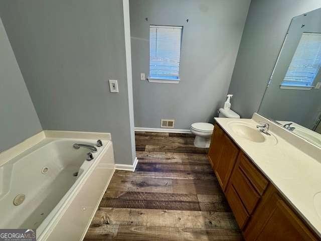 bathroom with hardwood / wood-style floors, vanity, toilet, and a bath