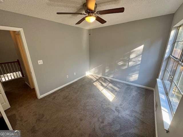 carpeted spare room featuring a textured ceiling and ceiling fan