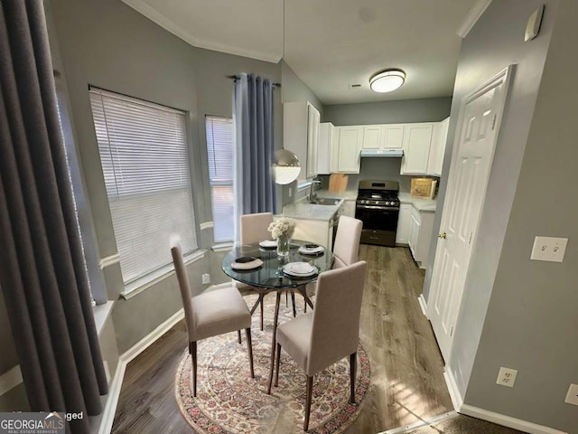 dining space featuring dark hardwood / wood-style flooring, crown molding, and sink