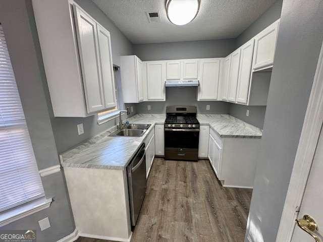 kitchen with sink, dark wood-type flooring, a textured ceiling, white cabinets, and appliances with stainless steel finishes