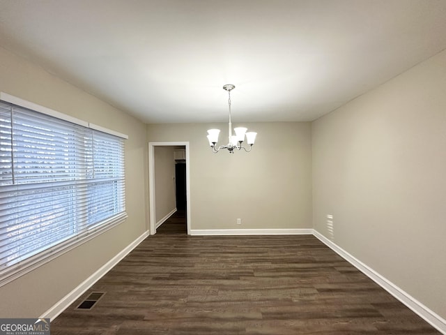 unfurnished dining area with a notable chandelier and dark hardwood / wood-style floors