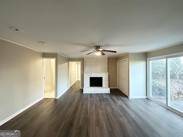 unfurnished living room featuring ceiling fan, dark hardwood / wood-style flooring, crown molding, and a brick fireplace