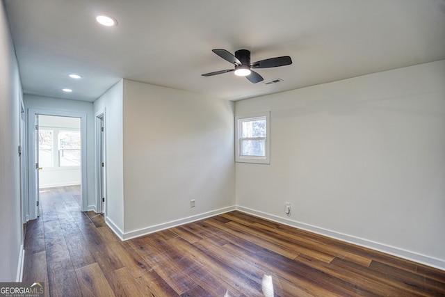 empty room with ceiling fan, a healthy amount of sunlight, and dark hardwood / wood-style floors