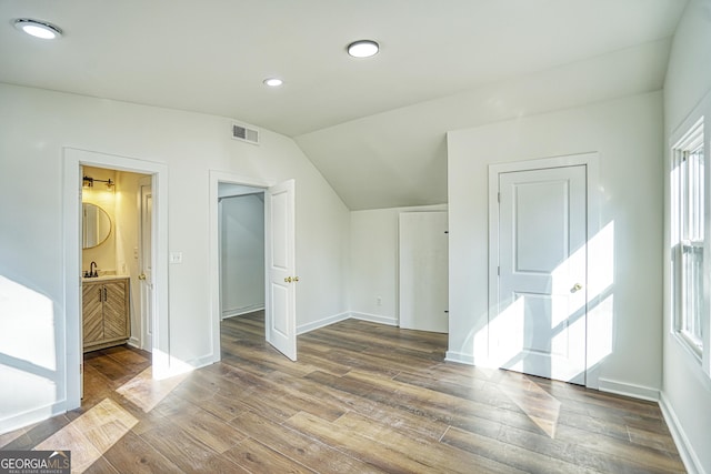 interior space featuring wood-type flooring, ensuite bath, lofted ceiling, and sink