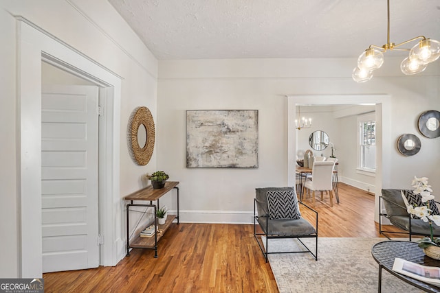 living area featuring a chandelier, a textured ceiling, and hardwood / wood-style flooring