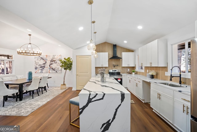 kitchen featuring white cabinetry, vaulted ceiling, wall chimney exhaust hood, and stainless steel range oven