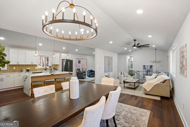 dining space with ceiling fan with notable chandelier, dark hardwood / wood-style flooring, and lofted ceiling