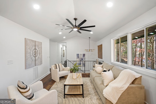 living room with ceiling fan with notable chandelier, vaulted ceiling, and light wood-type flooring