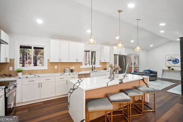 kitchen featuring stainless steel appliances, white cabinets, dark hardwood / wood-style floors, a kitchen island, and lofted ceiling