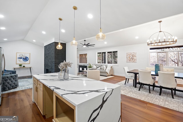 kitchen with ceiling fan with notable chandelier, dark wood-type flooring, decorative light fixtures, a fireplace, and lofted ceiling