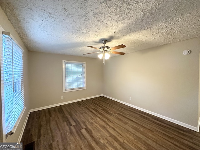 unfurnished room featuring ceiling fan, dark wood-type flooring, and a textured ceiling