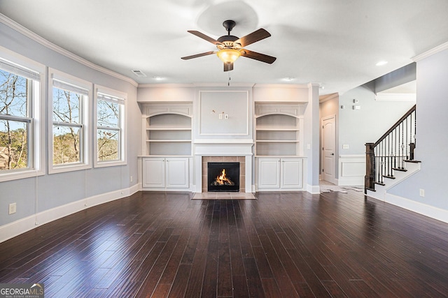 unfurnished living room with ceiling fan, built in features, ornamental molding, and a tile fireplace