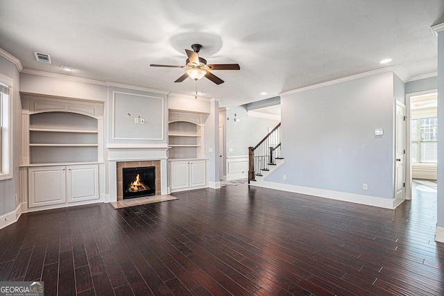 unfurnished living room featuring ceiling fan, dark hardwood / wood-style floors, ornamental molding, and a fireplace