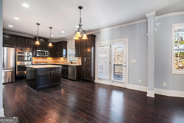 kitchen with backsplash, crown molding, pendant lighting, a kitchen island, and appliances with stainless steel finishes