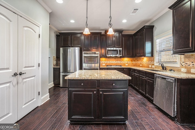 kitchen featuring pendant lighting, a center island, sink, dark brown cabinetry, and stainless steel appliances