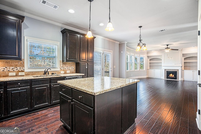 kitchen featuring pendant lighting, a center island, ornamental molding, and sink