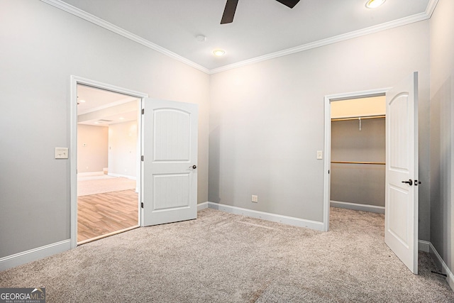 unfurnished bedroom with a walk in closet, light colored carpet, ceiling fan, crown molding, and a closet