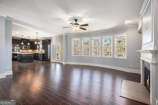 unfurnished living room featuring dark wood-type flooring, ceiling fan, a fireplace, and crown molding