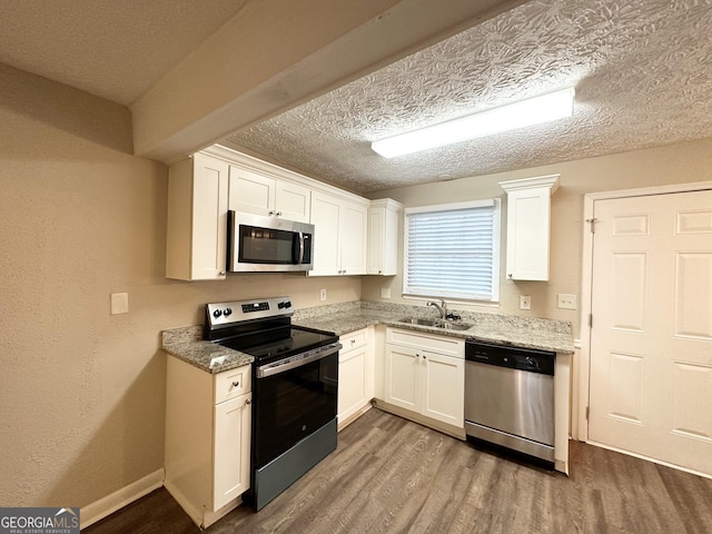 kitchen with white cabinetry, sink, stainless steel appliances, and hardwood / wood-style flooring