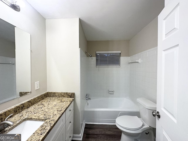 full bathroom with vanity, hardwood / wood-style flooring, toilet, and tiled shower / bath combo