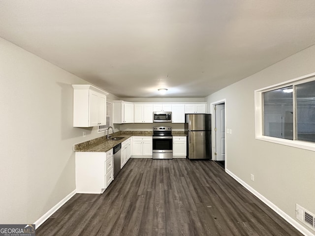 kitchen with sink, stainless steel appliances, dark hardwood / wood-style flooring, dark stone counters, and white cabinets