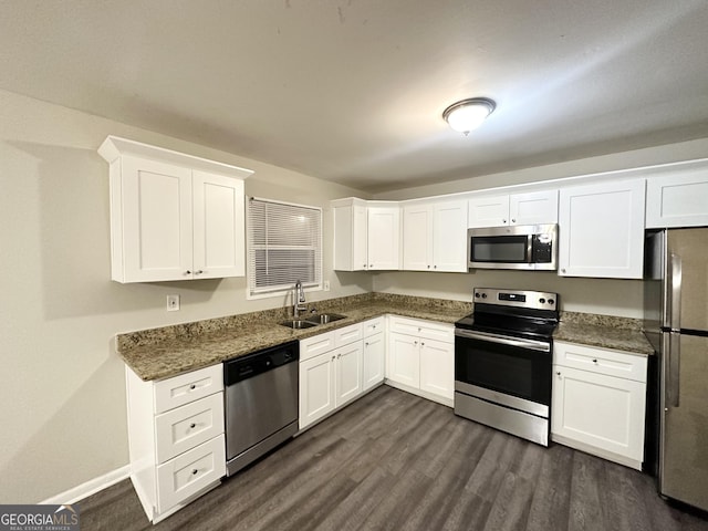 kitchen featuring white cabinetry, sink, dark hardwood / wood-style flooring, dark stone countertops, and appliances with stainless steel finishes