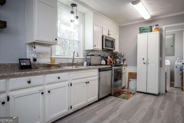 kitchen with stainless steel appliances, washer and clothes dryer, crown molding, white cabinets, and light hardwood / wood-style floors