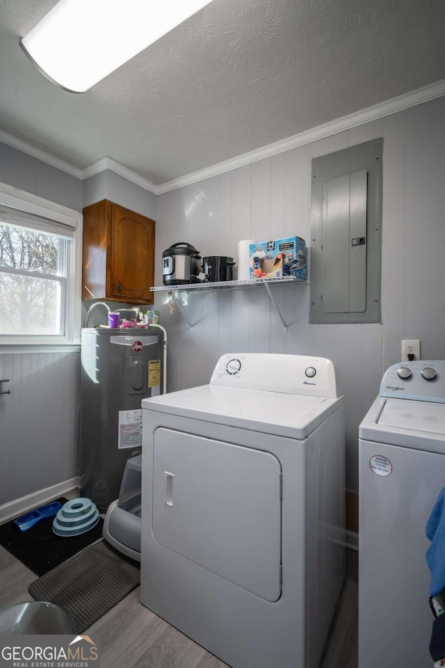 clothes washing area with washer and clothes dryer, electric water heater, electric panel, light hardwood / wood-style flooring, and a textured ceiling