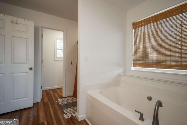 bathroom with a washtub and wood-type flooring