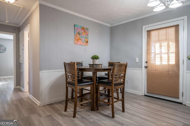 dining space with light wood-type flooring and ornamental molding