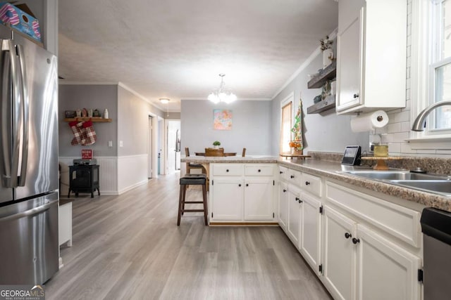 kitchen featuring a breakfast bar, sink, kitchen peninsula, white cabinetry, and stainless steel appliances