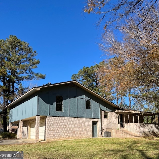 exterior space with a yard, cooling unit, and a garage