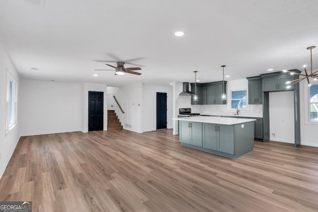 kitchen featuring decorative light fixtures, gray cabinets, a kitchen island, and wall chimney range hood