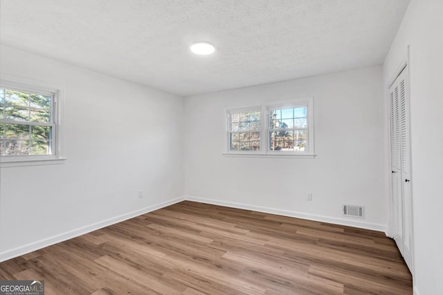 unfurnished bedroom featuring a closet, wood-type flooring, and multiple windows