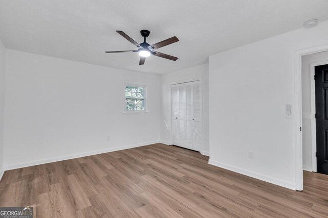 empty room with ceiling fan and light hardwood / wood-style flooring