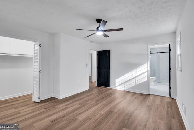 unfurnished bedroom featuring light hardwood / wood-style flooring, ceiling fan, a textured ceiling, connected bathroom, and a closet