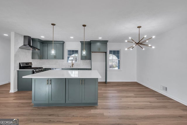 kitchen with pendant lighting, a center island, stainless steel gas range, wall chimney exhaust hood, and tasteful backsplash