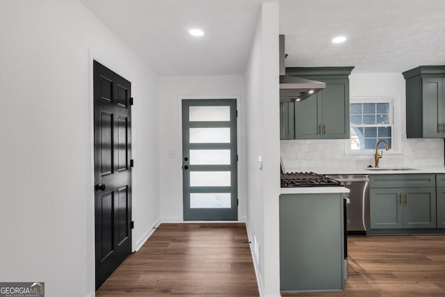 kitchen with wall chimney range hood, decorative backsplash, sink, and dark hardwood / wood-style floors