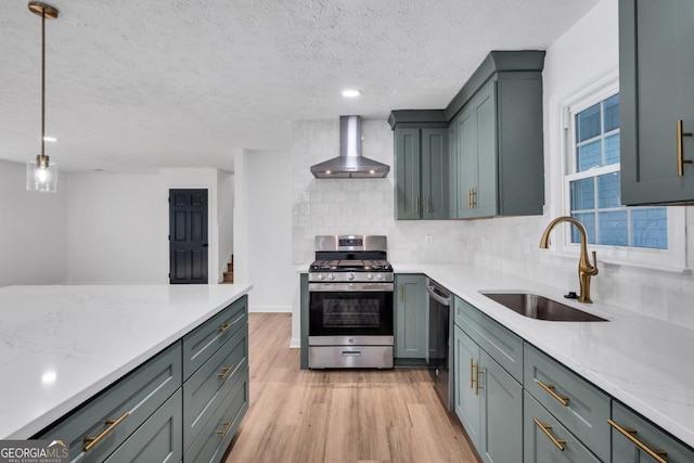 kitchen with sink, stainless steel appliances, wall chimney range hood, backsplash, and pendant lighting