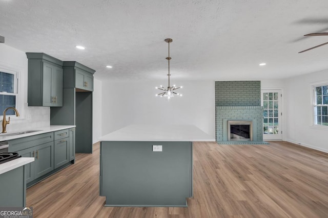 kitchen featuring backsplash, sink, a brick fireplace, and a textured ceiling