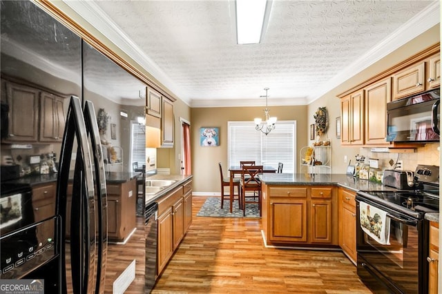 kitchen featuring hanging light fixtures, black appliances, a notable chandelier, and ornamental molding