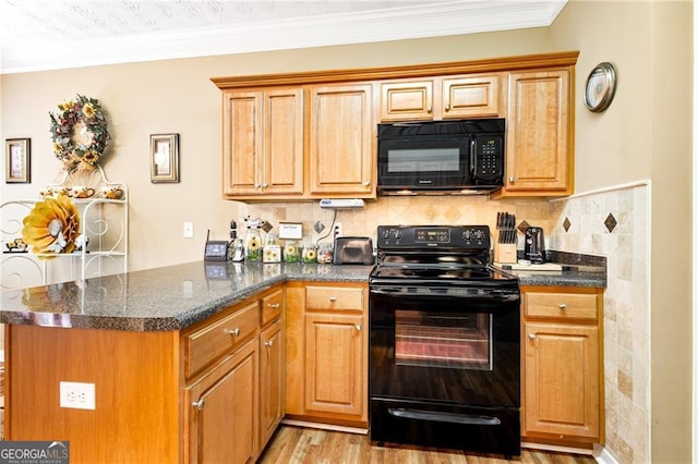 kitchen featuring kitchen peninsula, dark stone counters, light wood-type flooring, black appliances, and ornamental molding