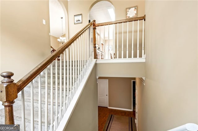 staircase with hardwood / wood-style flooring and a notable chandelier