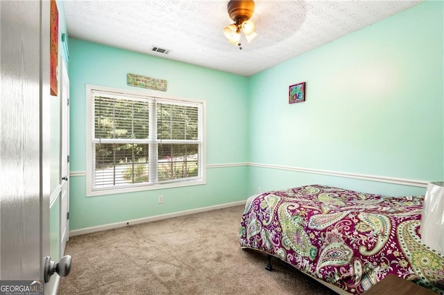 bedroom with ceiling fan, light colored carpet, and a textured ceiling