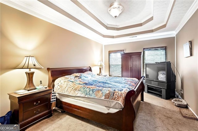 bedroom with light colored carpet, ornamental molding, and a tray ceiling